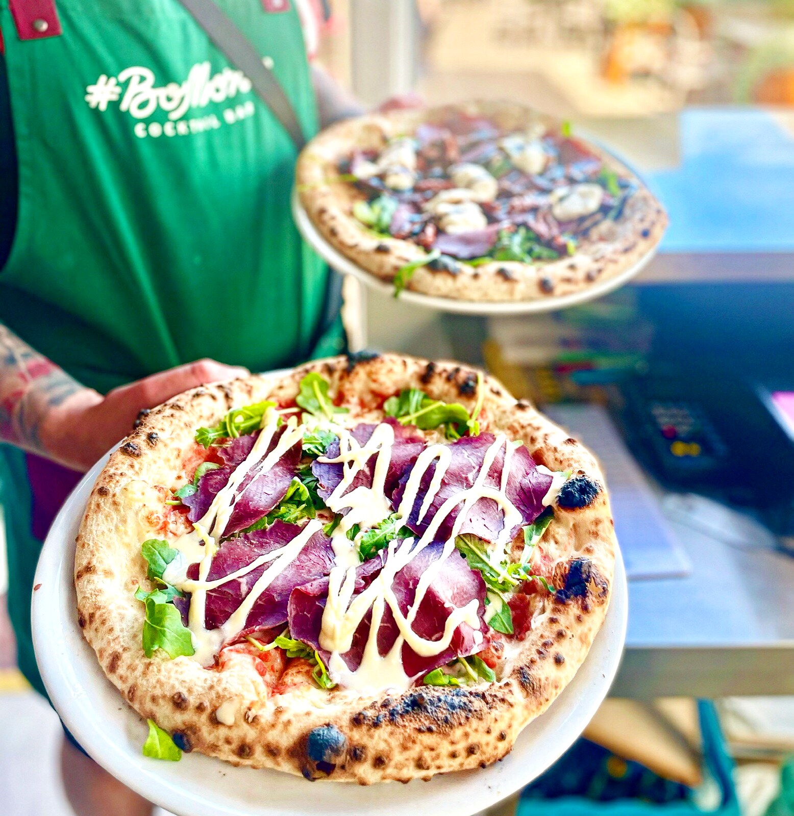 Kelner #BoMorze Cocktail Bar serwuje dwie pizze — bresaola z rukolą