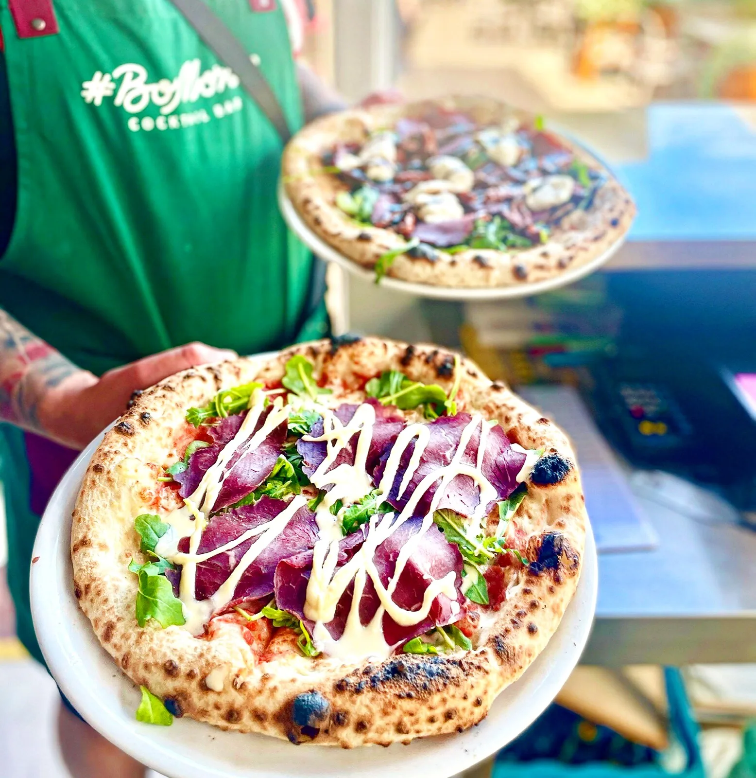 Kelner BoMorze serwuje dwie pizze — bresaola z rukolą